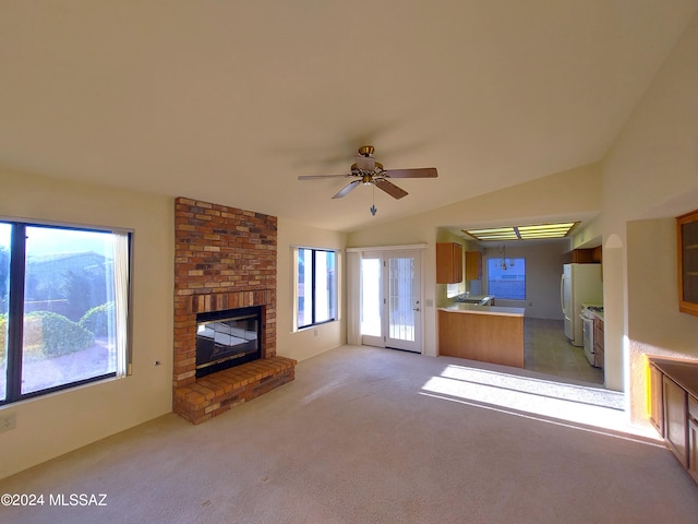 unfurnished living room with a brick fireplace, lofted ceiling, light carpet, and ceiling fan