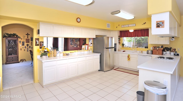 kitchen with light carpet, white appliances, kitchen peninsula, and white cabinetry