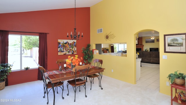 dining space featuring a chandelier, light colored carpet, and high vaulted ceiling