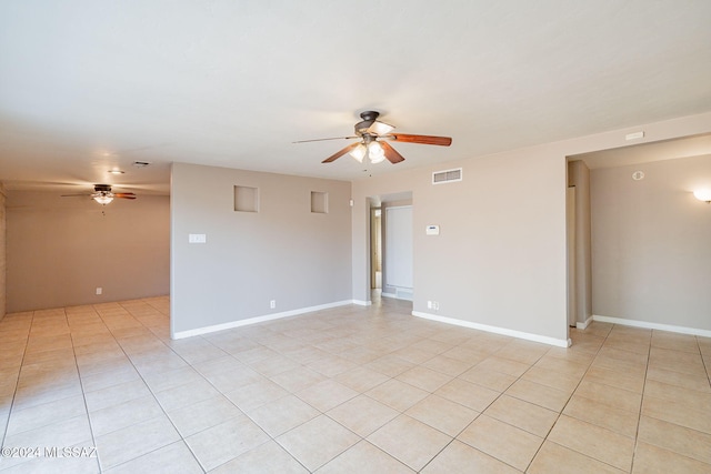 empty room with visible vents, ceiling fan, baseboards, and light tile patterned floors