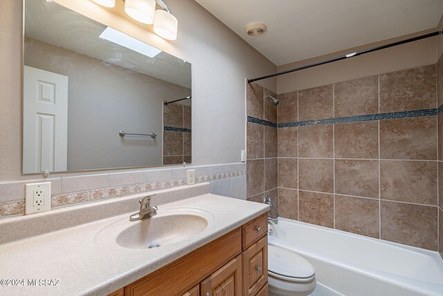 bathroom featuring toilet, tile walls, shower / washtub combination, and vanity
