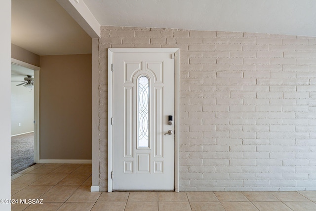 tiled entryway featuring a ceiling fan and baseboards