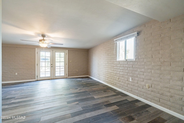 unfurnished room featuring a healthy amount of sunlight, brick wall, dark wood finished floors, and french doors