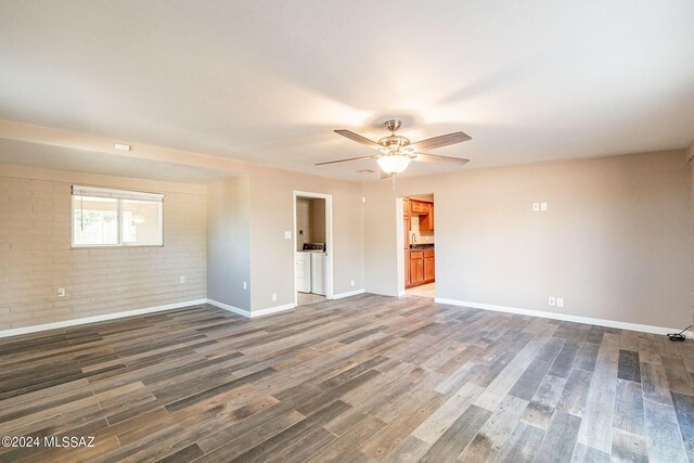 unfurnished room featuring baseboards, wood finished floors, ceiling fan, and brick wall