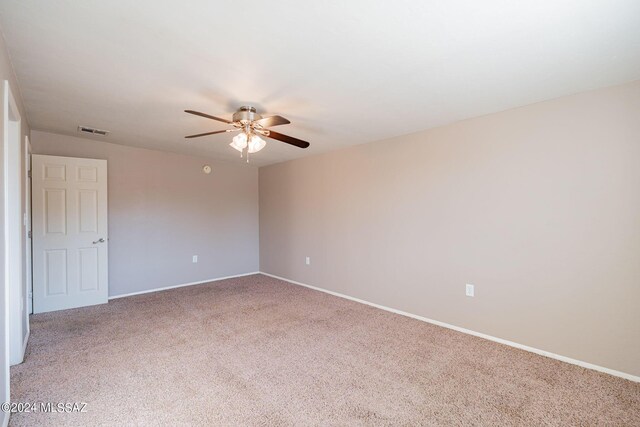carpeted empty room with baseboards, visible vents, and ceiling fan