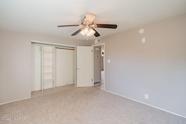 unfurnished bedroom featuring a closet, visible vents, ceiling fan, and light carpet