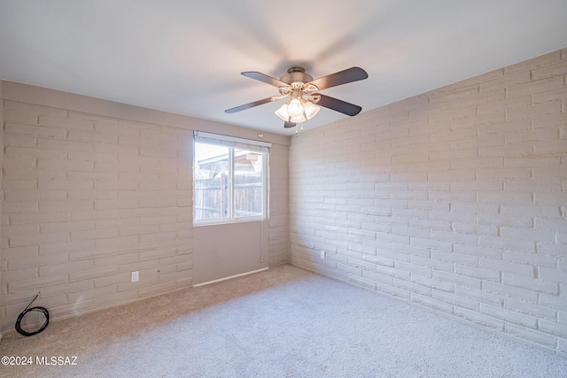 unfurnished room featuring carpet floors, brick wall, and a ceiling fan