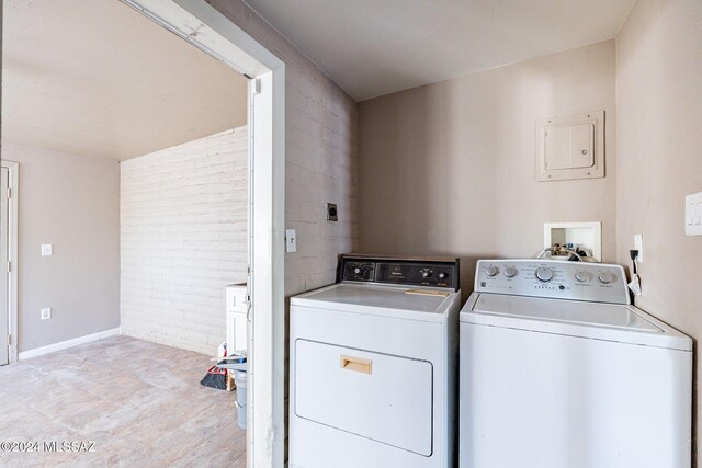 laundry room with brick wall, washer and clothes dryer, and baseboards