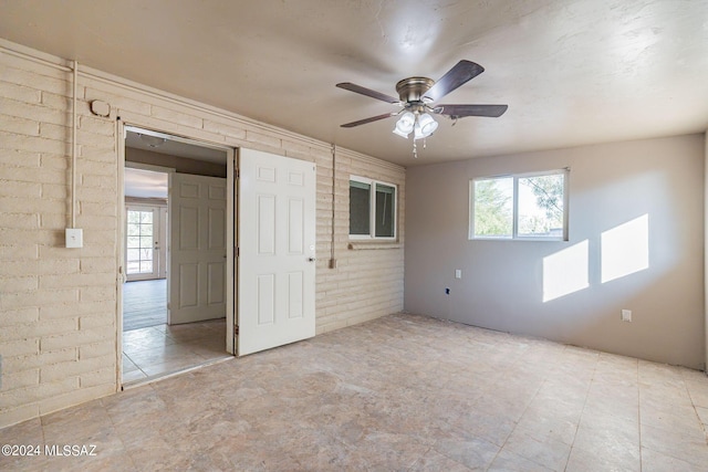 unfurnished bedroom with brick wall and ceiling fan