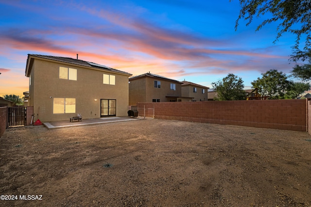 398 W Cedar Chase Dr, Green Valley, AZ 85614 - back of house at dusk with a patio area, a fenced backyard, solar panels, and stucco siding