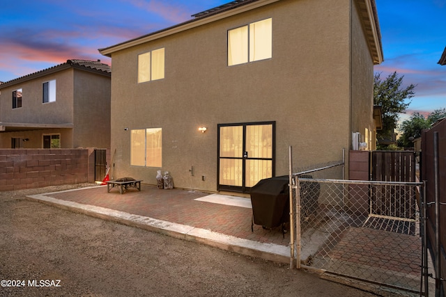 398 W Cedar Chase Dr, Green Valley, AZ 85614 - back of property at dusk featuring an outdoor fire pit, stucco siding, fence, and a gate