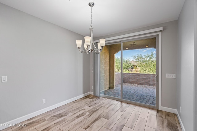 unfurnished room with light wood-type flooring and an inviting chandelier