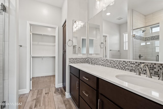 bathroom with wood-type flooring, vanity, backsplash, and an enclosed shower