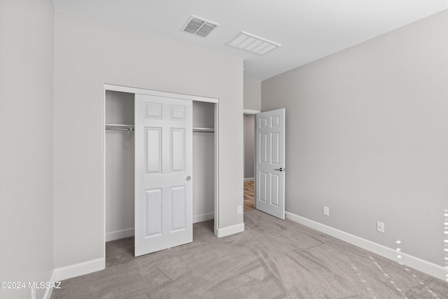 unfurnished bedroom featuring light carpet and a closet