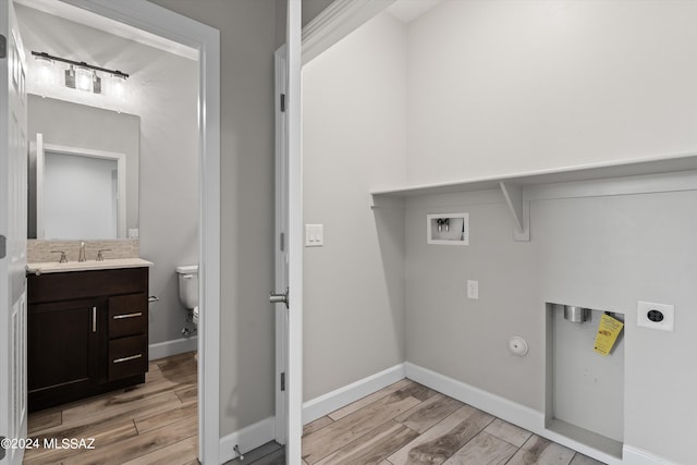 laundry area with light hardwood / wood-style floors, washer hookup, hookup for an electric dryer, gas dryer hookup, and sink