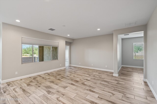 unfurnished room featuring light wood-type flooring and a healthy amount of sunlight