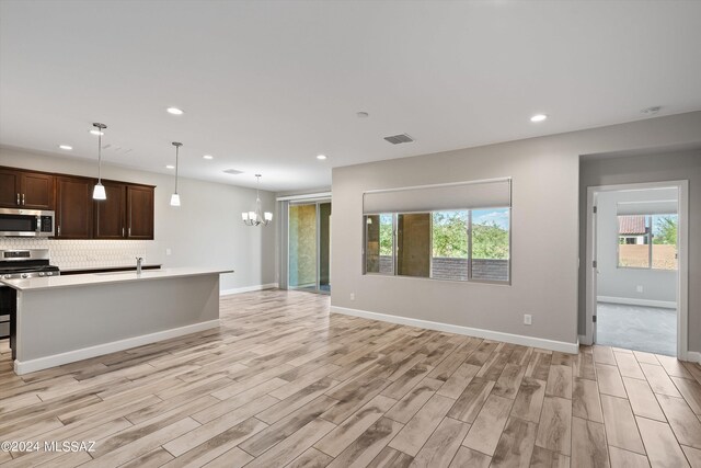 kitchen featuring light wood-type flooring, dark brown cabinetry, pendant lighting, and stainless steel appliances