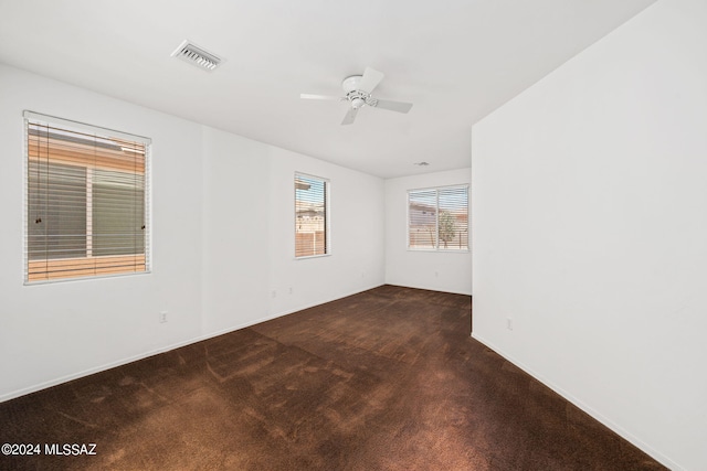 spare room featuring ceiling fan and dark colored carpet