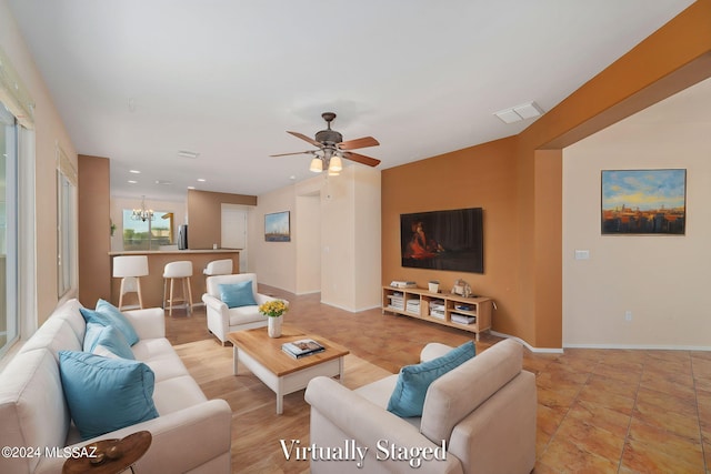 living room with ceiling fan with notable chandelier