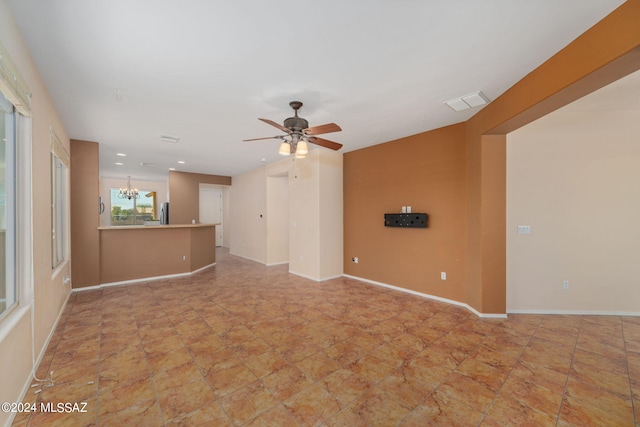 unfurnished living room with ceiling fan with notable chandelier