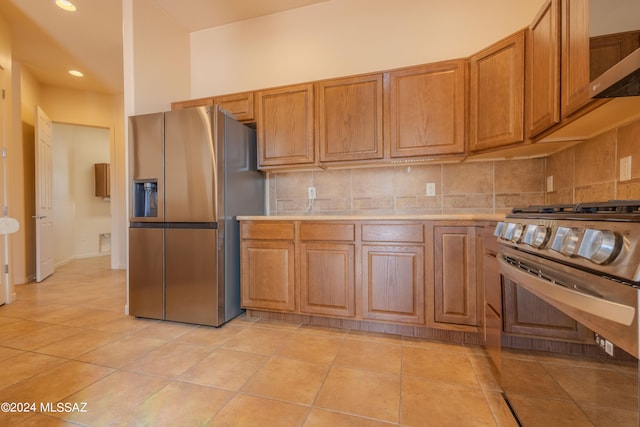 kitchen featuring appliances with stainless steel finishes, light tile patterned floors, and decorative backsplash