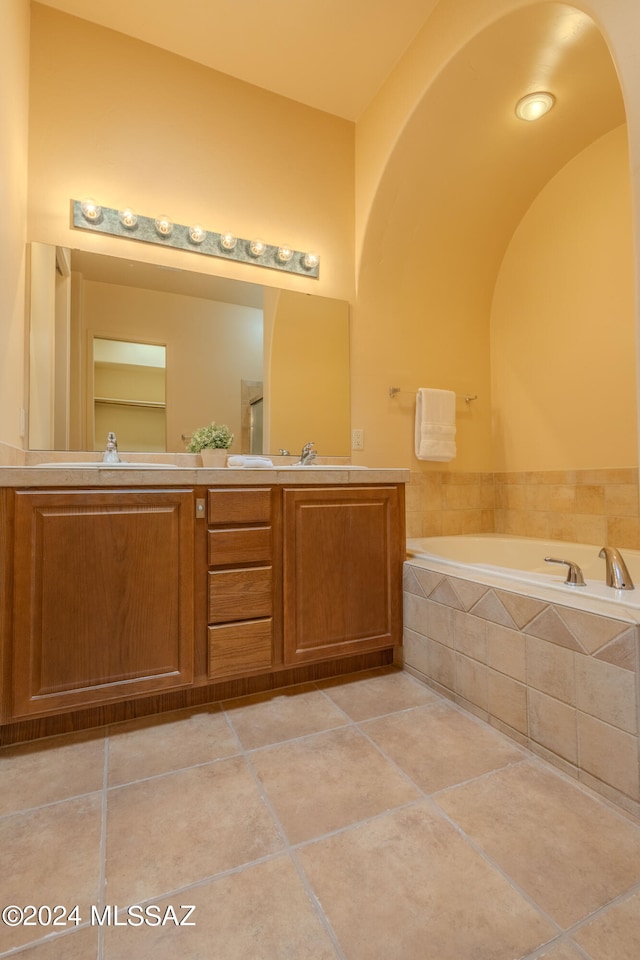 bathroom with vanity, tile patterned floors, and a relaxing tiled tub