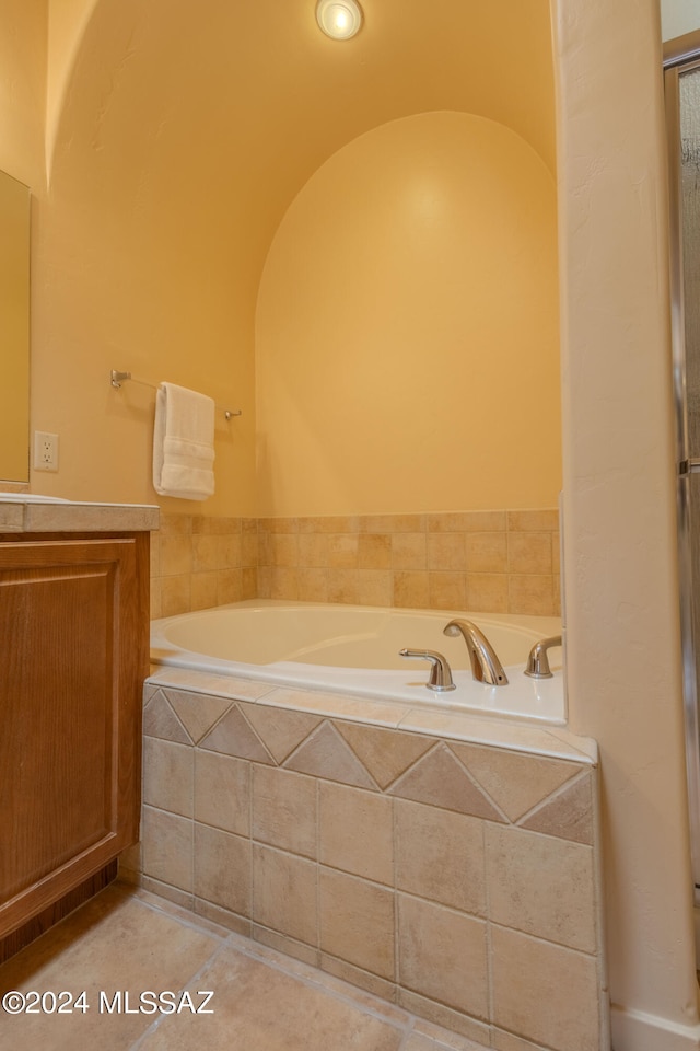 bathroom with tile patterned floors and a relaxing tiled tub