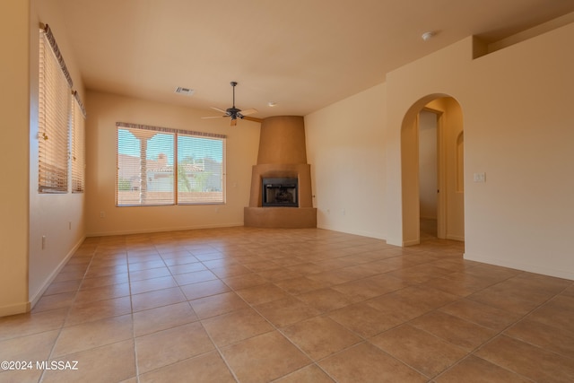 unfurnished living room featuring light tile patterned floors, a fireplace, and ceiling fan