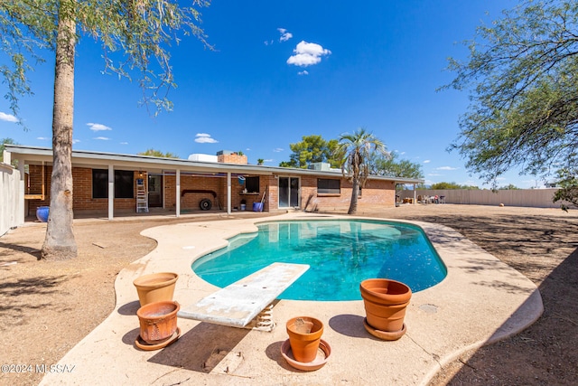 view of swimming pool featuring a patio area and a diving board