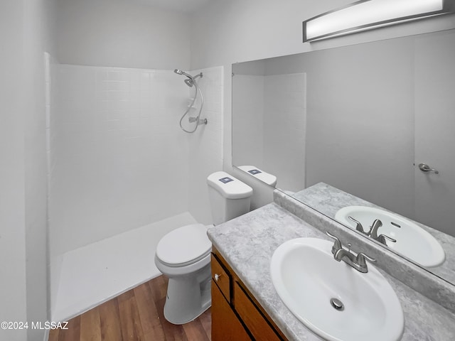 bathroom with wood-type flooring, vanity, toilet, and a shower