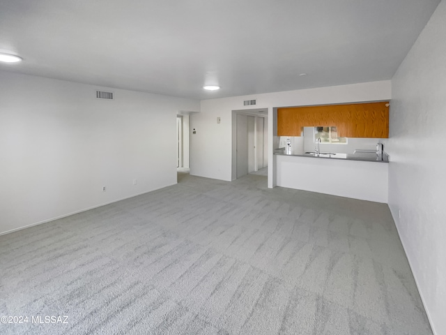 unfurnished living room with sink and light carpet