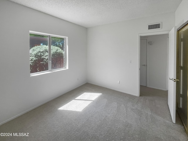 carpeted spare room featuring a textured ceiling