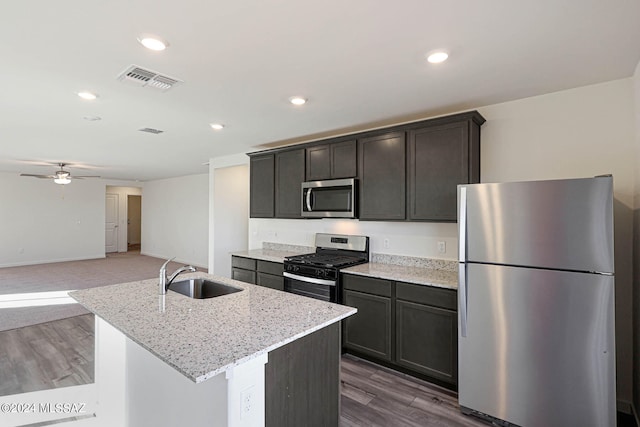 kitchen with appliances with stainless steel finishes, dark wood-type flooring, an island with sink, ceiling fan, and sink