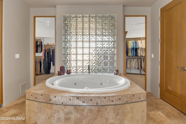 bathroom with tiled tub and tile patterned flooring