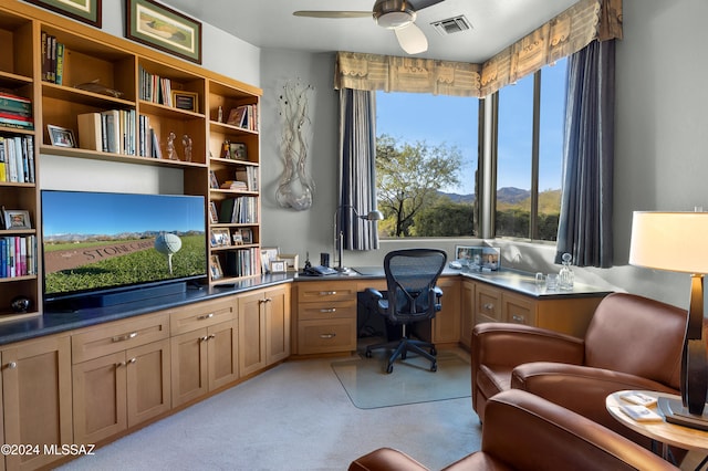 carpeted office featuring built in desk and ceiling fan