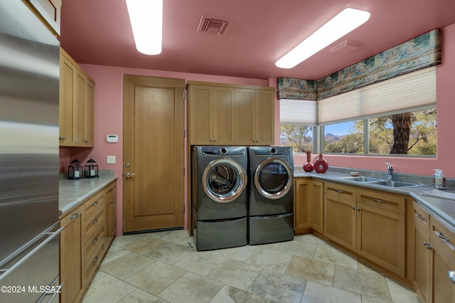 laundry room featuring cabinets, independent washer and dryer, and sink