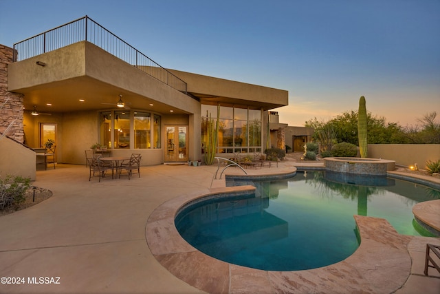 pool at dusk with an in ground hot tub, ceiling fan, and a patio