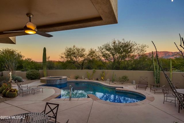 pool at dusk with an in ground hot tub, ceiling fan, and a patio area