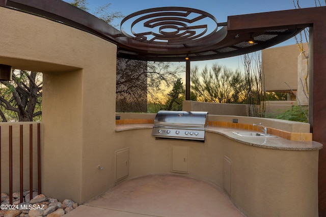 patio terrace at dusk with an outdoor kitchen, area for grilling, and sink