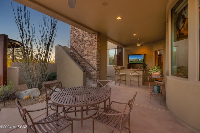 view of patio featuring an outdoor kitchen, ceiling fan, and a bar