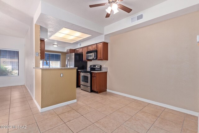 kitchen with ceiling fan, appliances with stainless steel finishes, a healthy amount of sunlight, and light tile patterned flooring