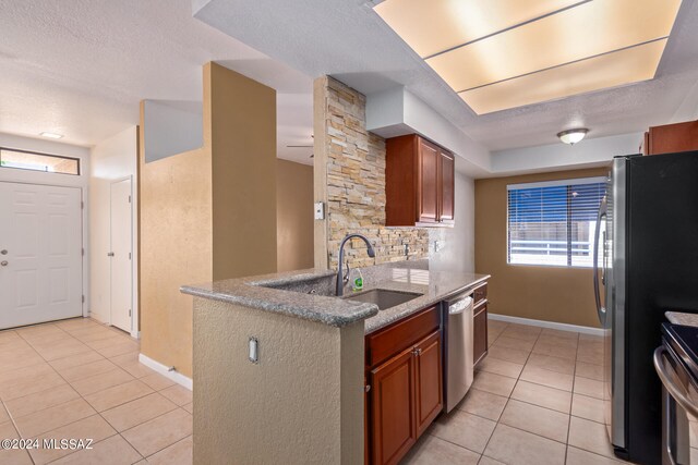 kitchen featuring a textured ceiling, sink, backsplash, appliances with stainless steel finishes, and light tile patterned floors