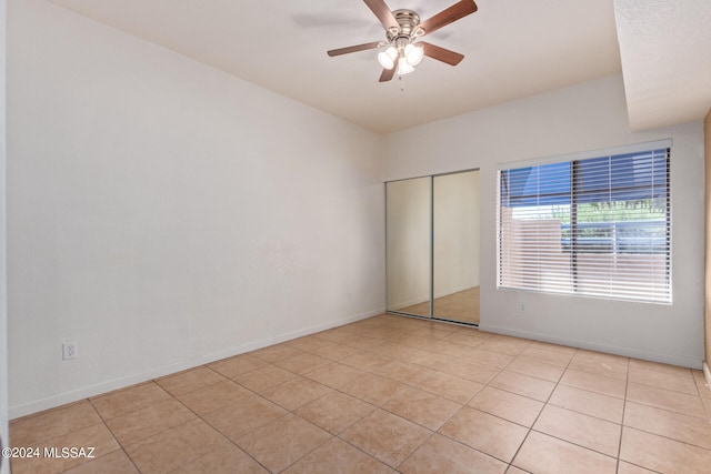 unfurnished bedroom with light tile patterned floors, ceiling fan, and a closet