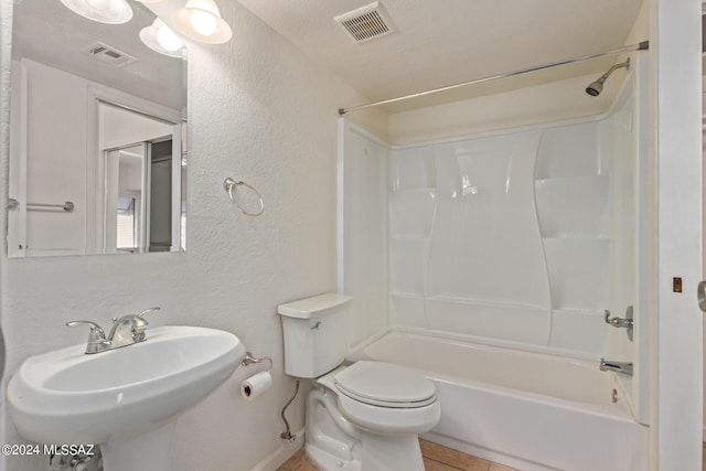 full bathroom featuring tub / shower combination, a textured ceiling, toilet, sink, and tile patterned floors