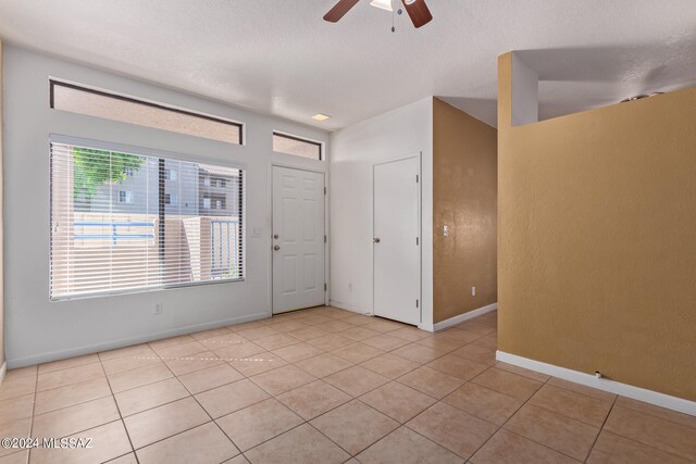 tiled empty room with a textured ceiling and ceiling fan