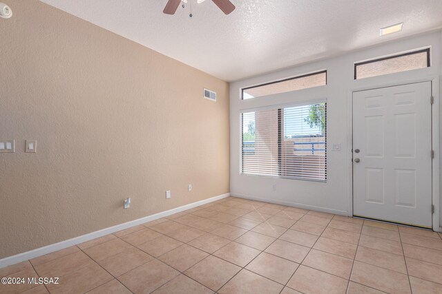 foyer entrance featuring ceiling fan, light tile patterned flooring, and a textured ceiling