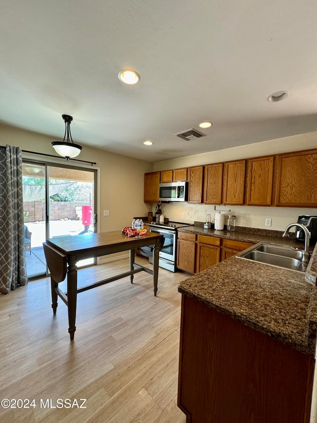 kitchen featuring appliances with stainless steel finishes, sink, hanging light fixtures, and light hardwood / wood-style floors