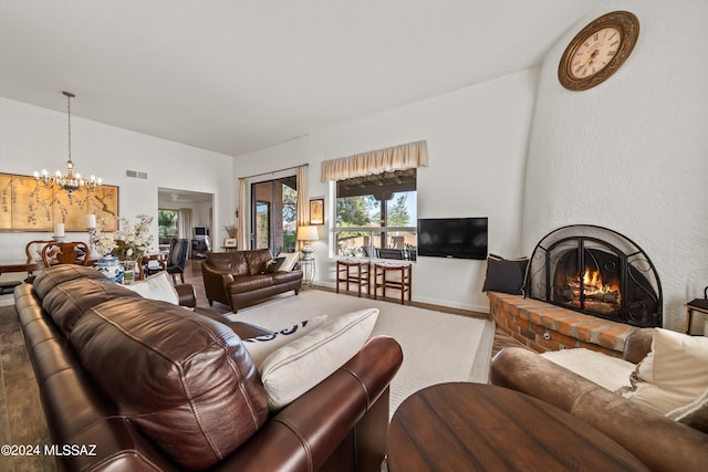 living room with hardwood / wood-style flooring, a chandelier, and a brick fireplace