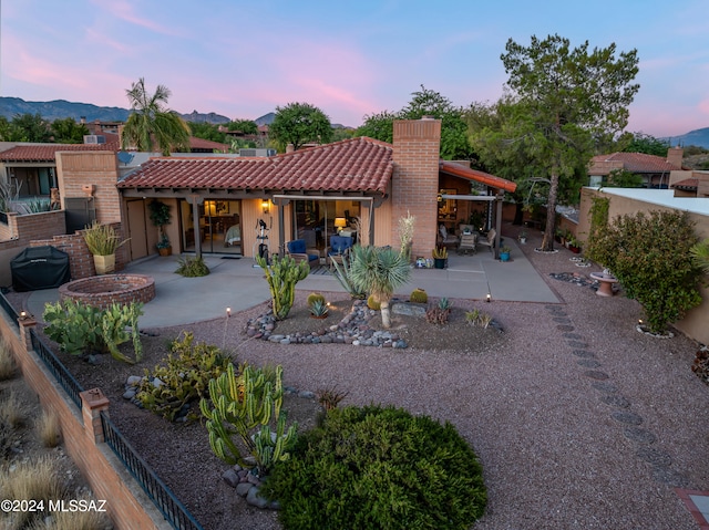 back house at dusk featuring a mountain view and a patio area