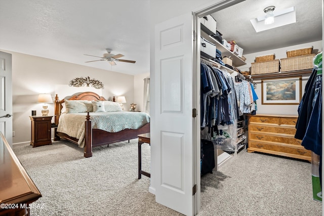 bedroom with ceiling fan, a textured ceiling, carpet floors, a skylight, and a closet